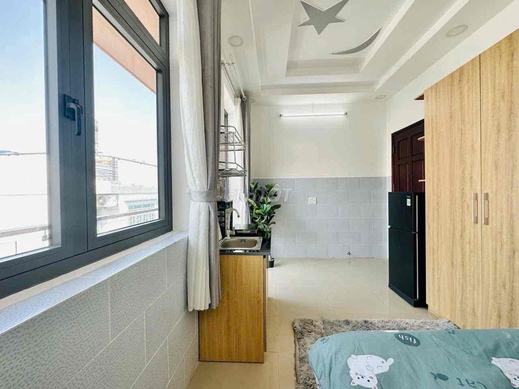 A studio with a balcony and a large window