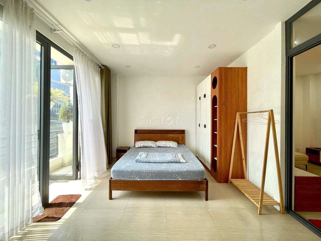 A full bedroom with a super-duper balcony view of green trees.